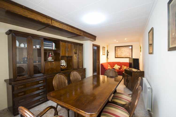 Acogedor comedor - sala de estar con mesa de madera para 6 comensales. Sofá y televisión.