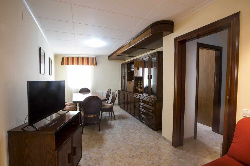 Acogedor comedor con mesa de madera para 6 comensales. Sofá y televisión.