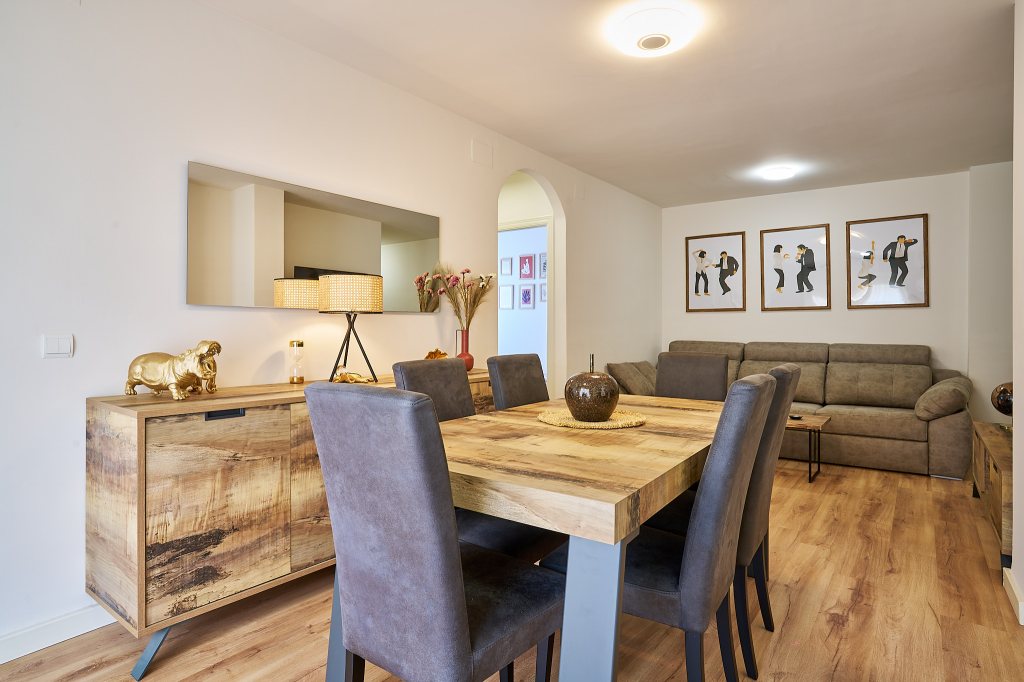 Elegante y confortable comedor con mesa de madera para 6 comensales y salón de estar con televisión