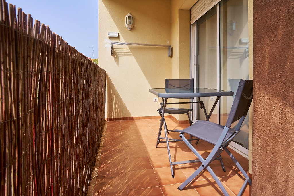 Terraza exterior con mesa, dos sillas y tendedero