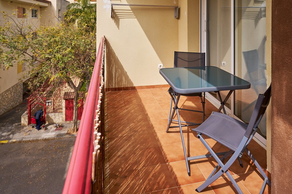 Terraza exterior con mesa, dos sillas y tendedero